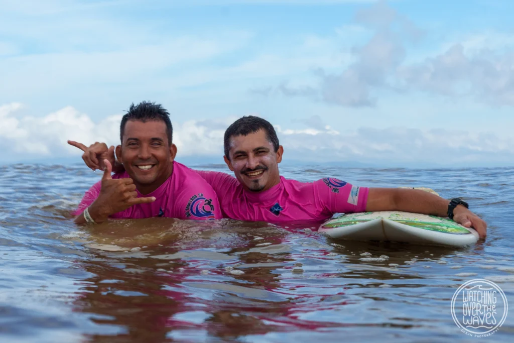 Dos hombres en el mar con tabla de surf