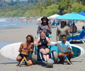Mujer en silla anfibia con grupo de instructores de surf
